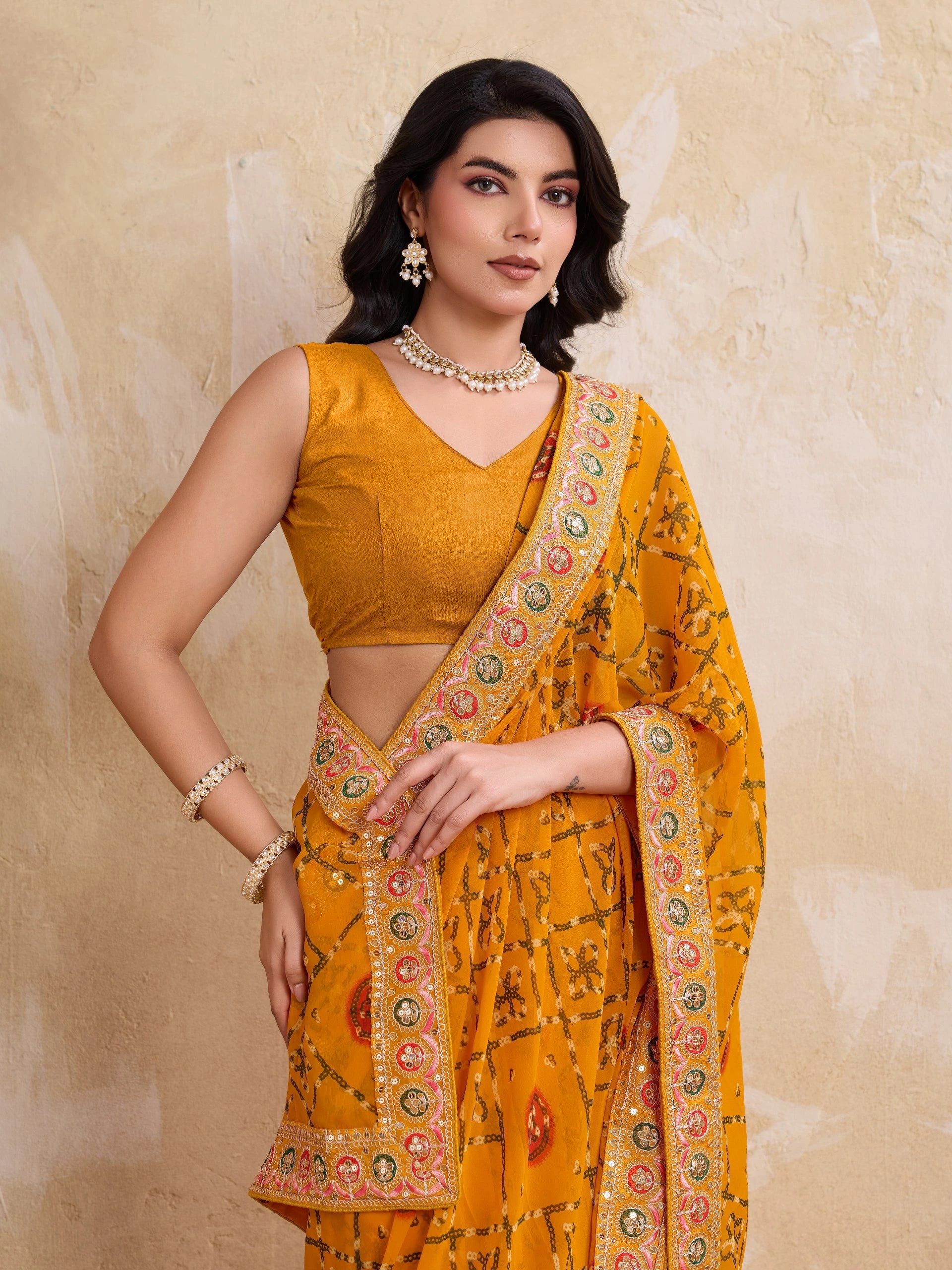 Woman wearing a mustard yellow saree with a floral pattern on a beige background